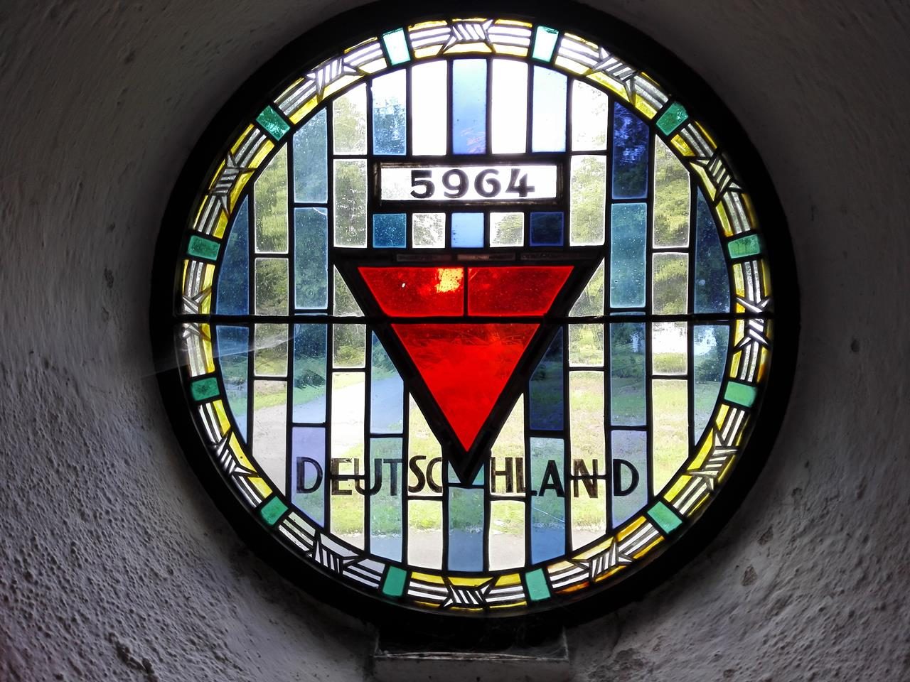 Kirchenfenster in der Gedenkstätte mit Häftlingsnummer und rotem Winkel